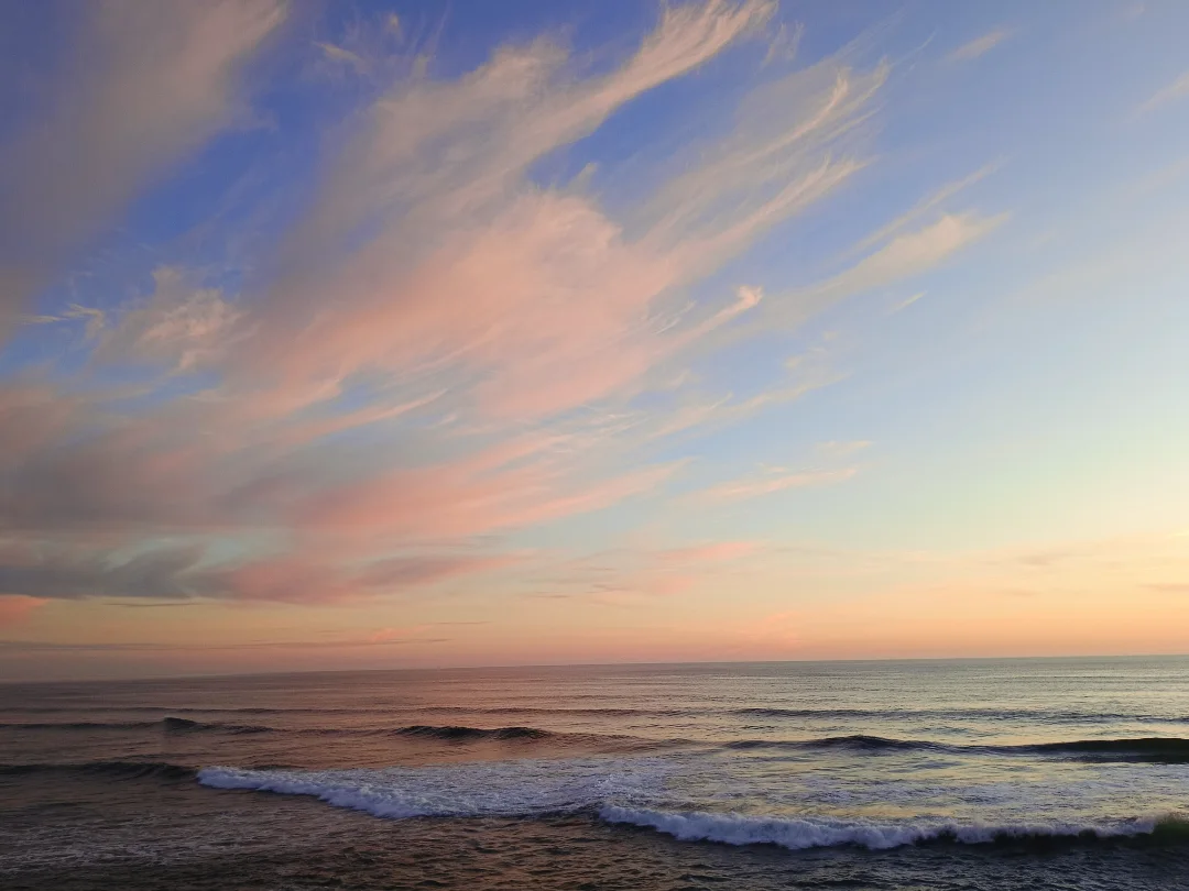 Wide ocean sunset with pink and blue streaked clouds