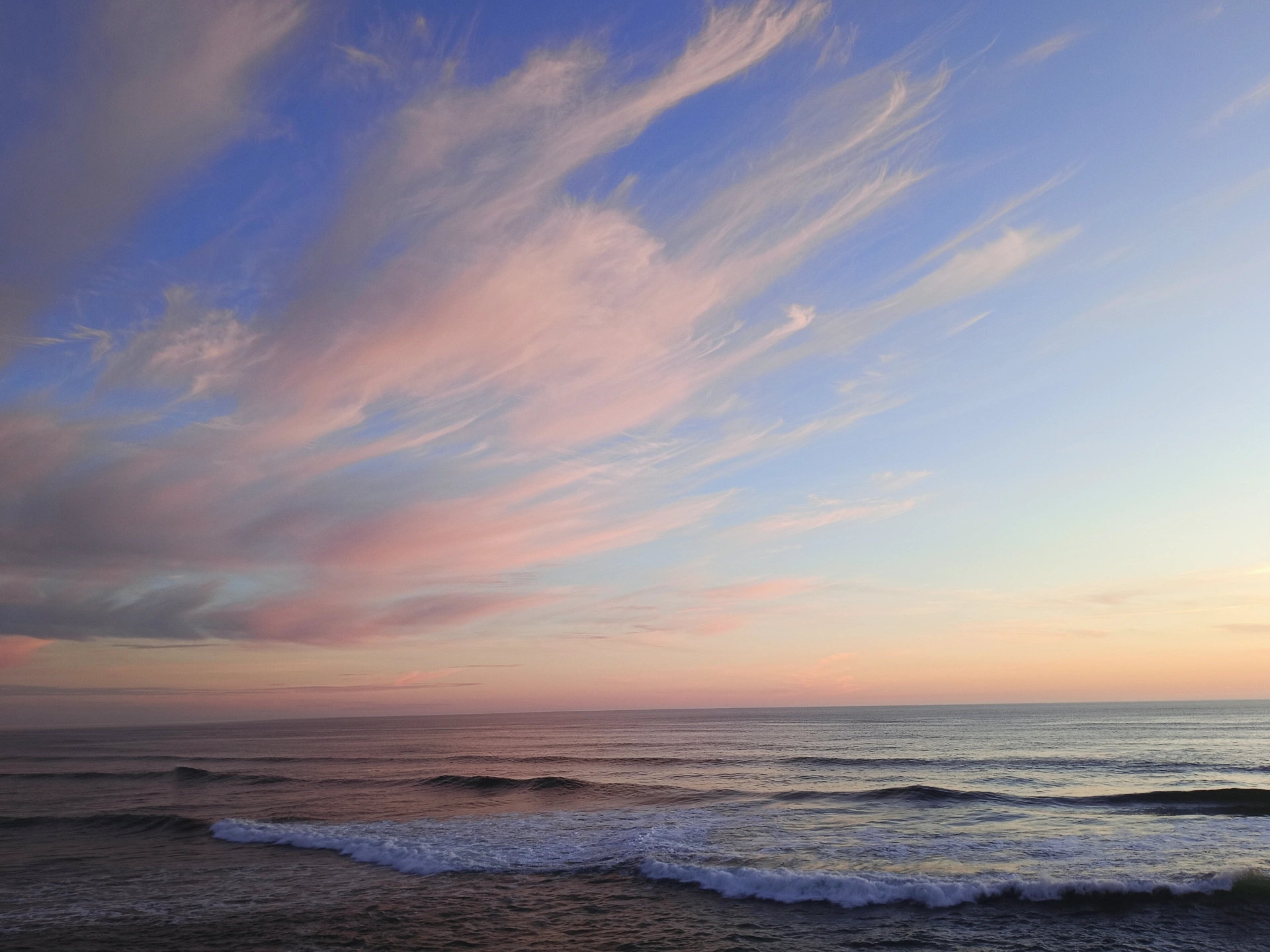 Pastel sunset sky over gentle ocean waves